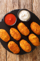 Salt cod croquettes croquetas de bacalao with sauces close up in the slate plate on the table. Vertical top view from above