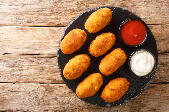 Spanish croquettes with salted cod served with sauces close-up on a slate plate on the table. horizontal top view from above