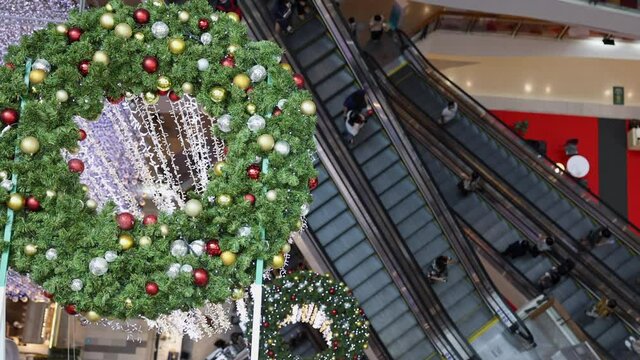 Beautiful Christmas wreath decoration in shopping mall and Crowd of People on an escalator. View from above