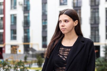 Fototapeta premium Portrait of the young woman in black clothing walking in the city.