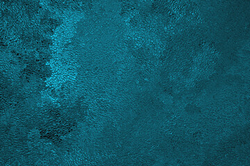 Blue winter background. Surface of ice crystals close up. Dark cyan tinted grainy backdrop. An abstract Christmas pattern of chaotic spots. Cold or frozen wallpaper. Macro