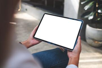 Mockup image of a woman holding digital tablet with blank white desktop screen in cafe