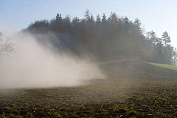 Scenic panorama landscape with waft of mist and freshly harvested field on a sunny autumn day. Photo taken November 12th, 2021, Zurich, Switzerland.