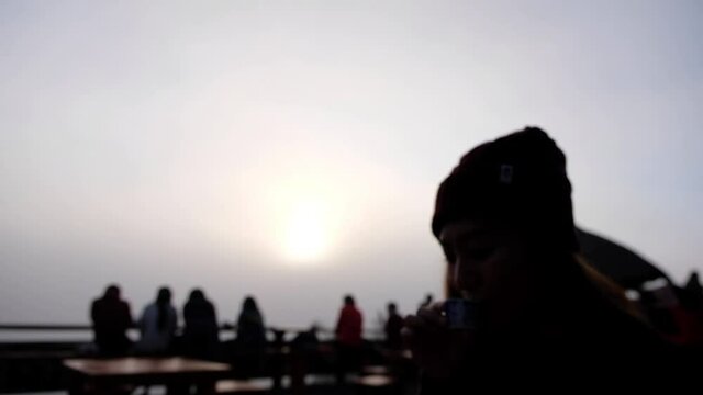 Slow motion blurred silhouette of a woman drinking tea while watching sunrise in the morning