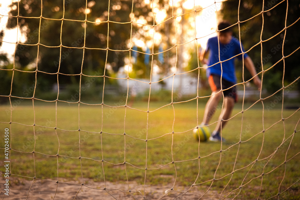 Wall mural Football player training in soccer field. Young footballer practicing on football field.