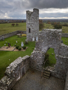 Aerial view of Oughterard church ruins with round tower in the background and Arthur Guinness grave in the foreground. Co. Kildare. Ireland. November 2021