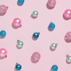 Creative Christmas pattern made of colorful Christmas baubles on a pastel pink background. Minimal New Year flat lay concept.