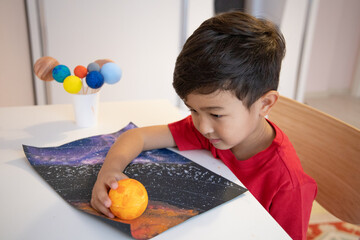 Happy preschooler holding handmade model of the sun. 3D solar system. Homeschool education. Astronomy objects.