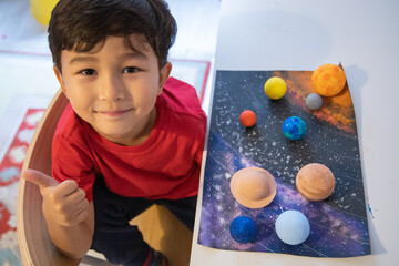 Happy preschooler made a solar system model. Handmade models of planets. 3D solar system. Homeschool education. Astronomy objects. Space color