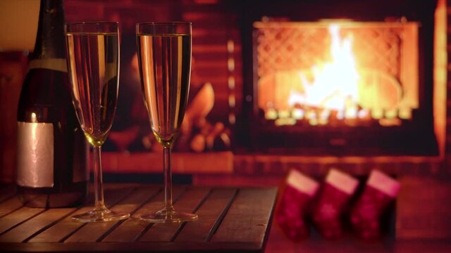 New Years Eve. Image of a bottle of champagne and two glasses of champagne against the background of the fireplace. New Year and Christmas mood. Holiday.	
