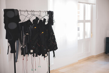 some electrostimulation vests hanging on a coat rack.
