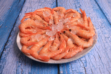 Portion of cooked white prawns from Huelva on blue old wooden background