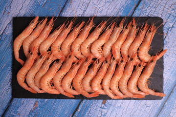 Portion of cooked white prawns from Huelva on blue old wooden background