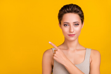 Portrait of attractive shine girl demonstrating copy empty blank space isolated over bright yellow color background