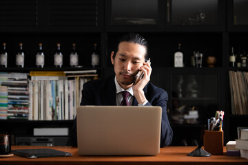 Fototapeta na wymiar スマホで話すアジア人(日本人）ビジネスマン男性　コピースペースあり 