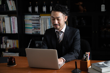 Handsome Asian (Japanese) businessman man looking down at his computer, copy space to the left.