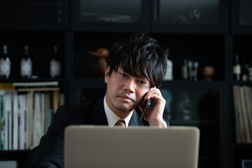 スマホで話すアジア人(日本人）ビジネスマン男性　コピースペースあり　アップ