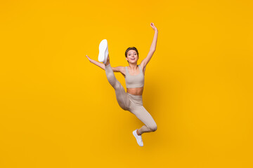 Full length body size view of pretty cheerful girl jumping working out shaping weight loss isolated over bright yellow color background