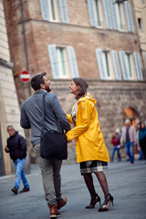Obraz premium A young couple in love having a good time while walking the old city and chatting. Walk, rain, city, relationship