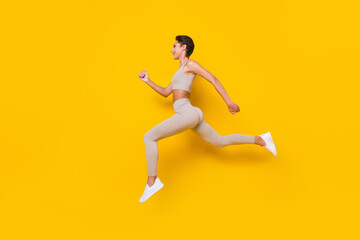 Fototapeta na wymiar Profile photo of sportive runner lady jump run wear cropped top leggings shoes isolated yellow color background