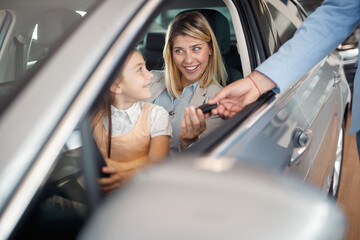 Woman  receives the keys to a  car from a sales manager