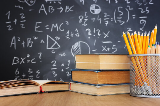 Pencils and graduation hat infront of blackboard with formulas. education concept