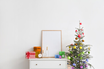Christmas tree with rainbow decor near chest of drawers in room. Concept of Christmas and LGBT