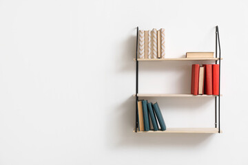 Modern shelves with books hanging on light wall