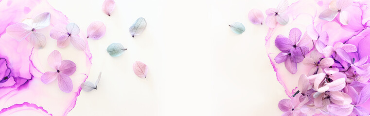 Creative image of pastel violet and pink Hydrangea flowers on artistic ink background. Top view with copy space