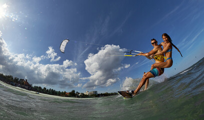 Lovely couple up on one kite board. Woman Riding On Kite surfer's Back and kiting on a sea