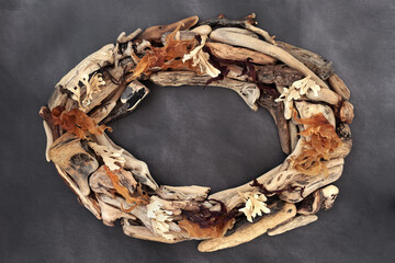 Driftwood and seaweed abstract oval wreath border frame on mottled grey grunge. Seaside art background. Natural composition. Top view, flat lay.
