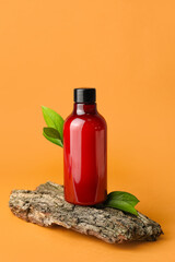 Bottle of shower gel and tree bark on color background