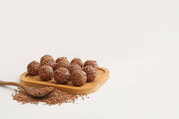 Board with tasty flax seed candies on white background