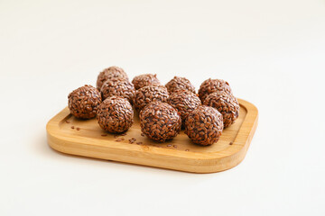 Board with tasty flax seed candies on white background