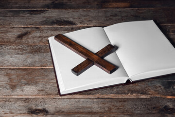 Open Holy Bible with cross on dark wooden background