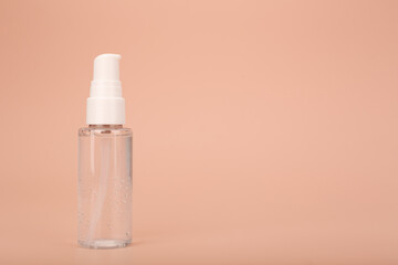 Transparent bottle with liquid face gel or cleaning foam against bright beige background with copy space