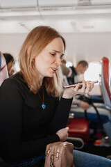 woman is records a voice message on the phone in a seat on board the plane. 