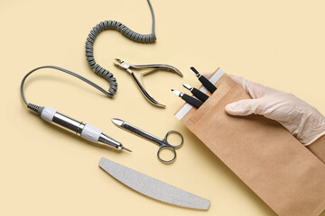 Female hand with manicure instruments on color background