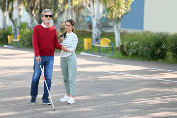 Blind senior man with his daughter walking outdoors