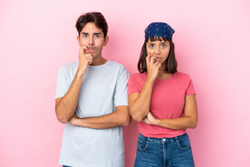 Young couple isolated on pink background having doubts while looking up