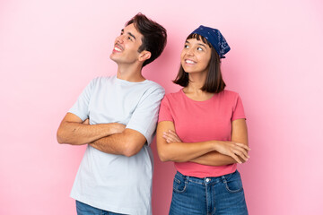 Young couple isolated on pink background looking up while smiling