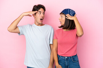 Young couple isolated on pink background with surprise and shocked facial expression