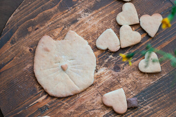 A large cookie in the shape of a cat's face on a wooden table.