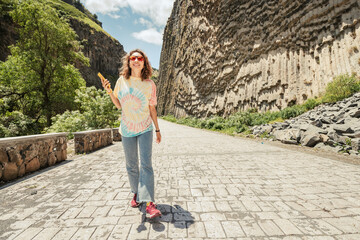 A woman with a smartphone walks along the Garni gorge in Armenia with the famous basalt columns...