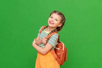 A beautiful little girl with a school bag on an isolated background. A joyful schoolgirl. Copy...