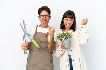 Young mixed race gardeners holding a plant and pruning shears isolated on white background...