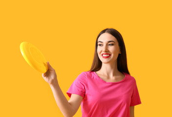 Beautiful young woman playing frisbee on color background