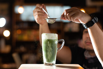 puring matcha powder in latte in cafe mood