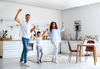 Happy interracial family dancing in kitchen