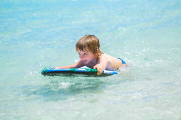 Fototapeta na wymiar Young surfer, happy young boy in the ocean on surfboard